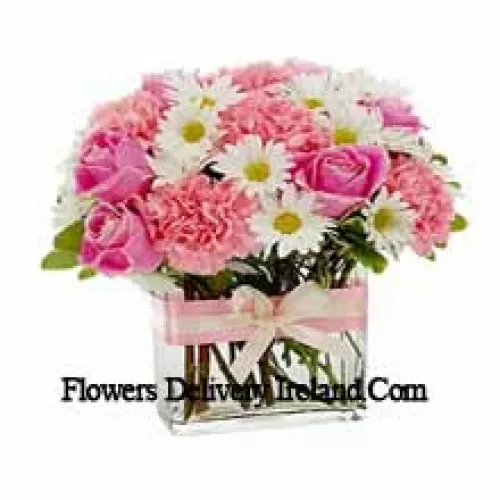 Roses roses, oeillets roses et diverses fleurs blanches de saison arrangées magnifiquement dans un vase en verre