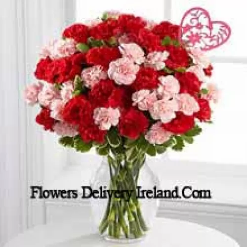 44 Carnations ( 18 Red And 18 Pink ) With Seasonal Fillers And Heart Stick In A Glass Vase